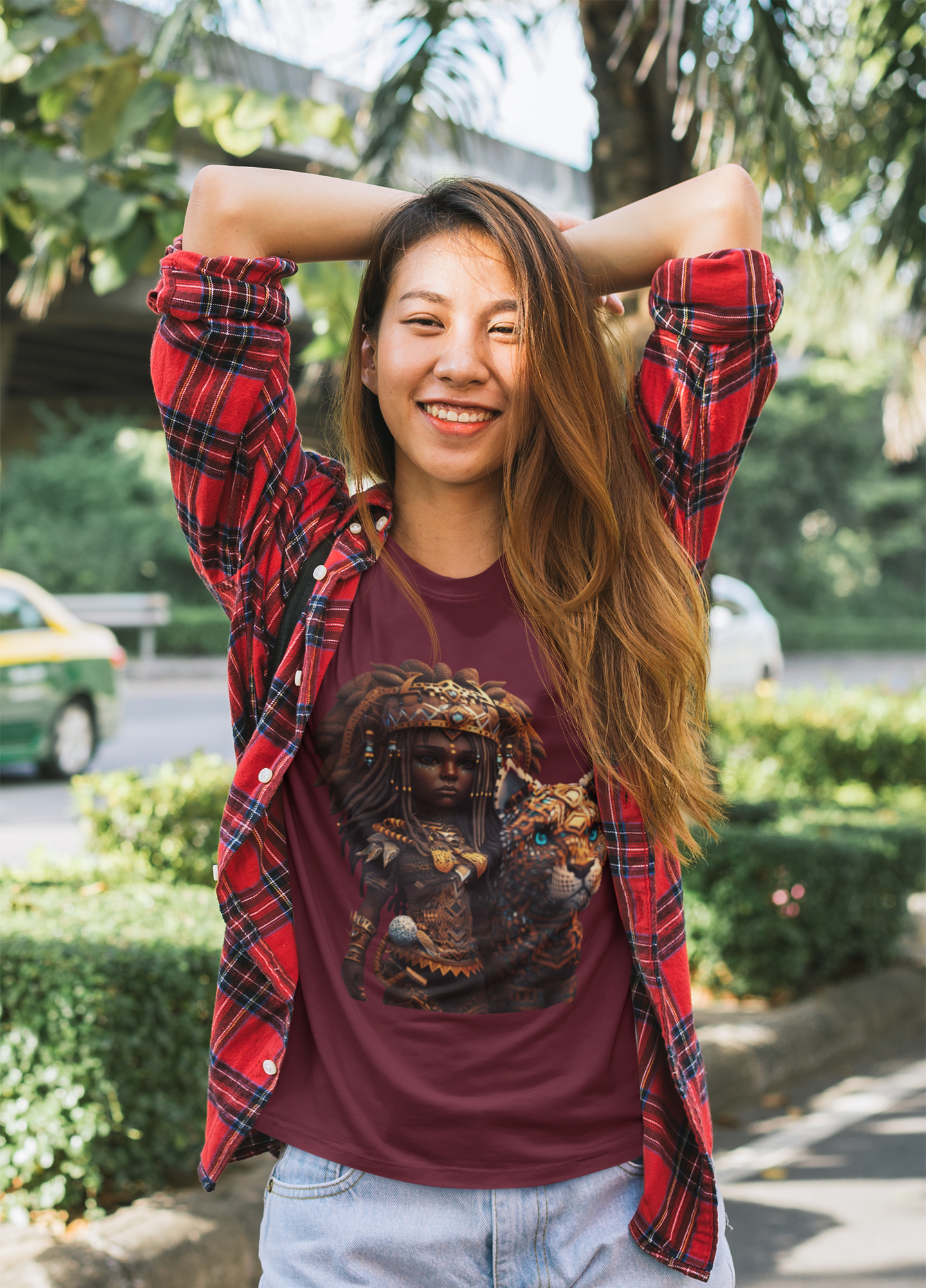 maroon colour t-shirt which has a design of a pop anime African princess with her leopard pet worn by a cheerful woman posing in the street